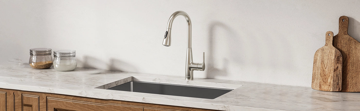 A sleek JOMOO pull-down faucet in matte black arcs over a deep, satin-finish single-bowl sink, both set flush in a pristine white countertop.